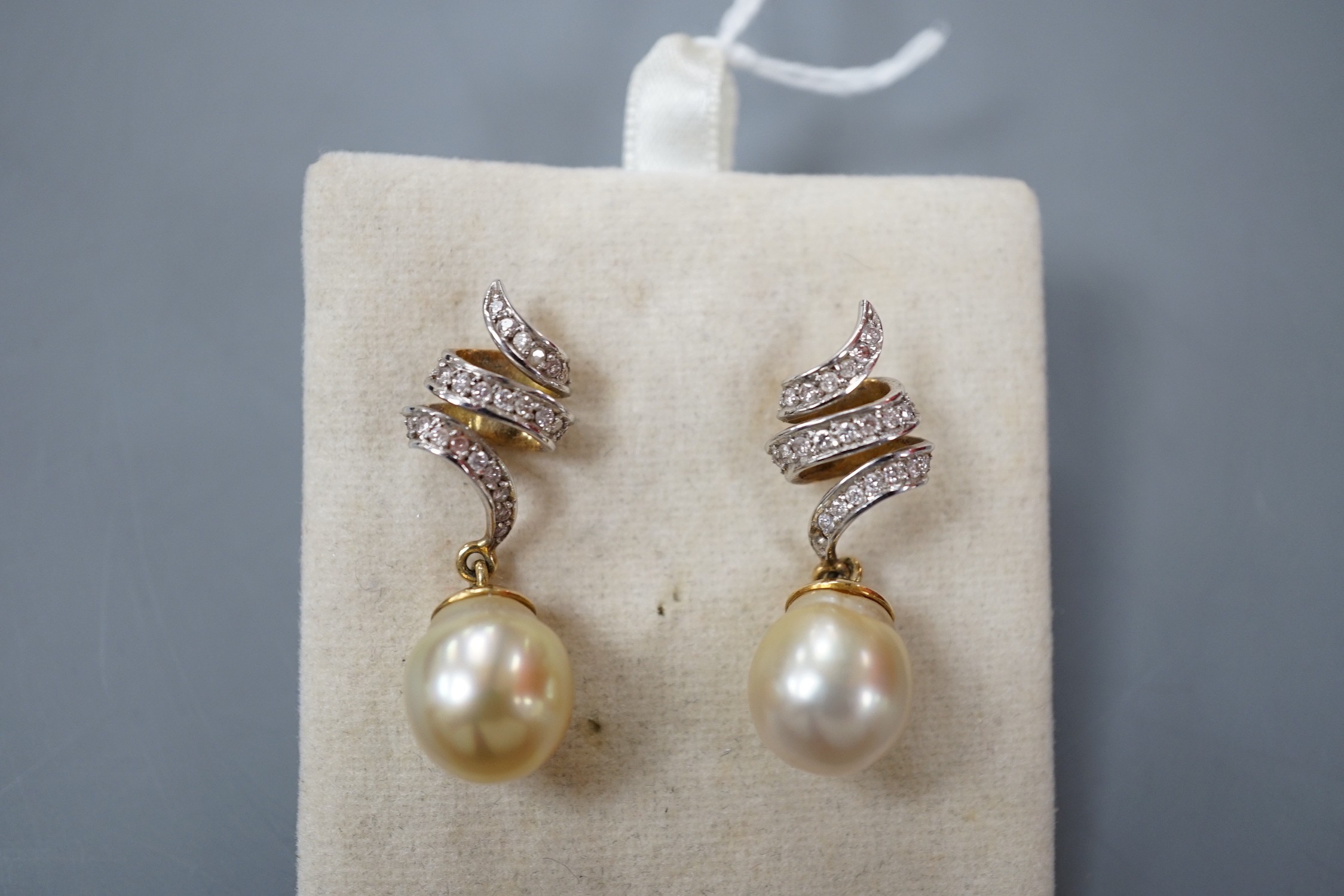A modern pair of yellow metal, cultured pearl and diamond set scroll drop drop earrings, overall 34mm, gross weight 10.3 grams.